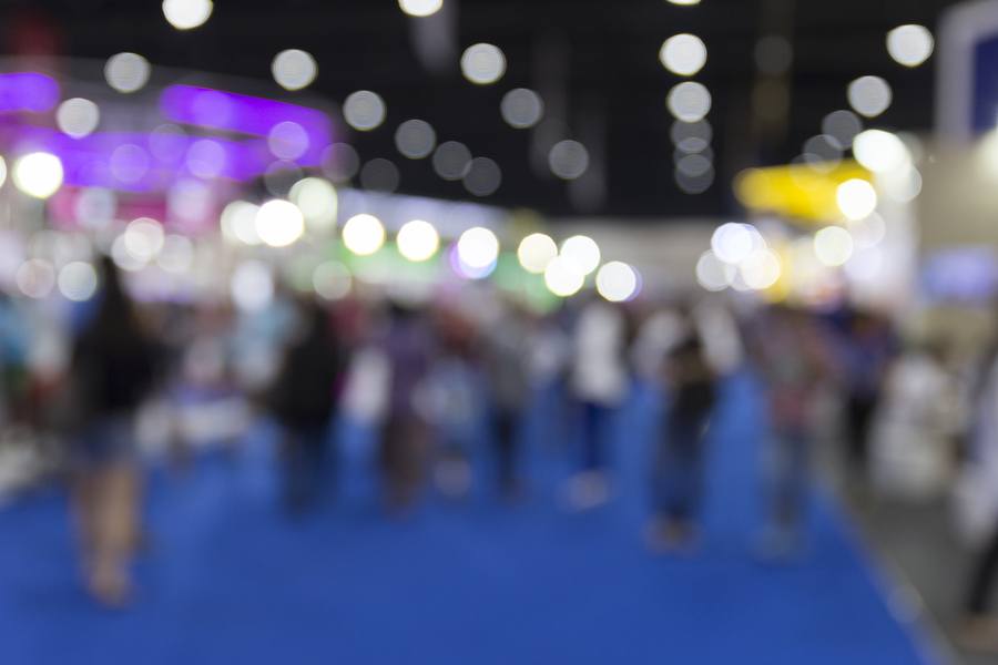 people in tradeshow exhibition hall building blur background